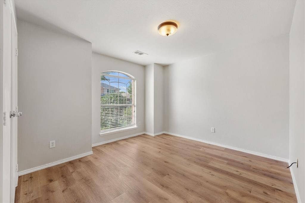 2004 Athabasca Falls Drive, Anna, TX 75409 Neutral-toned interior featuring wood-finish flooring, an arched window, and a flush-mount ceiling light