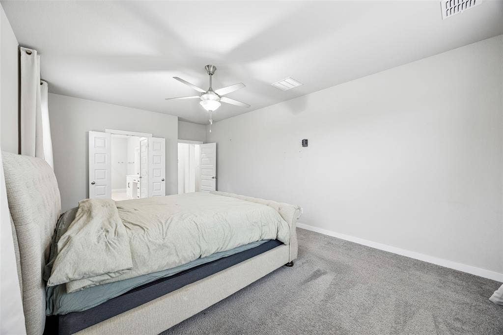 Room featuring neutral wall tones, carpeted flooring, a ceiling fan with integrated light fixture, and white dual-panel doors