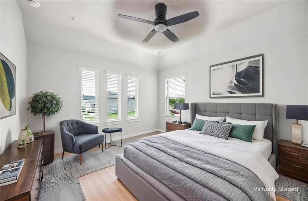 High ceilings featuring a recessed tray detail, multiple windows with horizontal blinds, and a matte black ceiling fan with integrated lighting