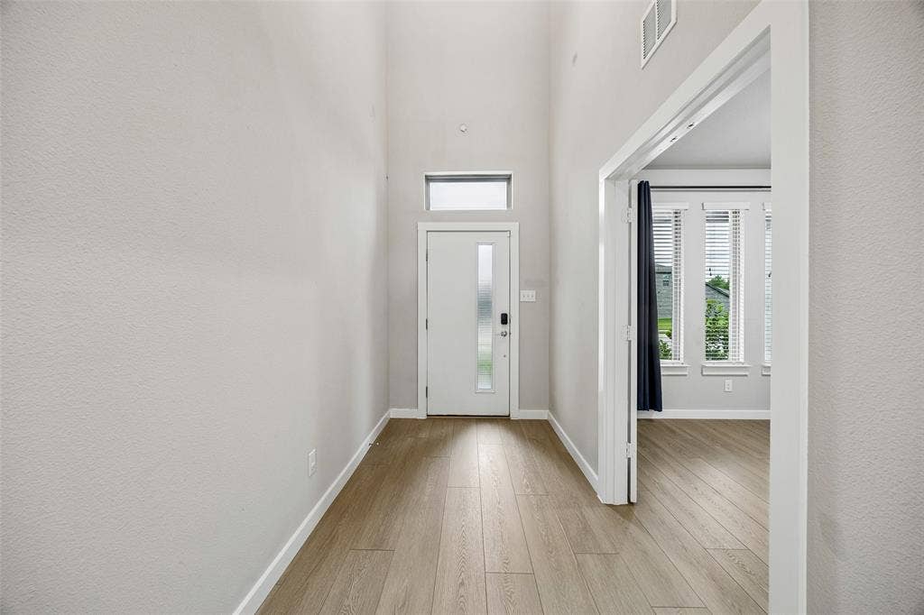 Entryway featuring high ceilings, wood-finish flooring, a front door with a vertical glass insert, and a transom window