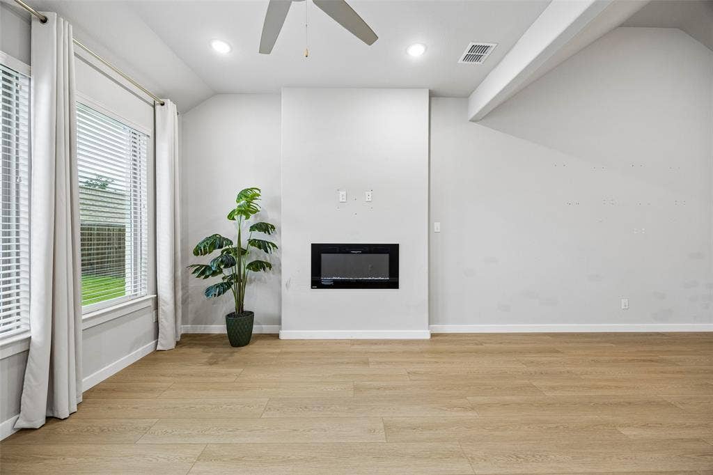 Vaulted ceilings, wood-finish flooring, recessed lighting, ceiling fan, and built-in electric fireplace