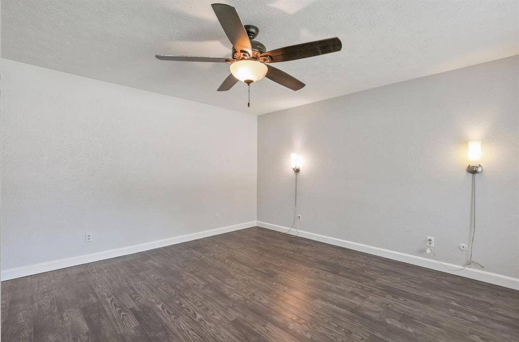9712 Summerhill Lane, Dallas, TX 75238 Room featuring wood-finish flooring, a central ceiling fan with integrated lighting, and two wall-mounted light fixtures
