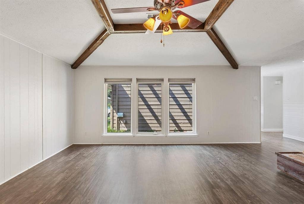 9712 Summerhill Lane, Dallas, TX 75238 Vaulted ceiling featuring exposed wood beams, triple window arrangement, and wood-finish flooring
