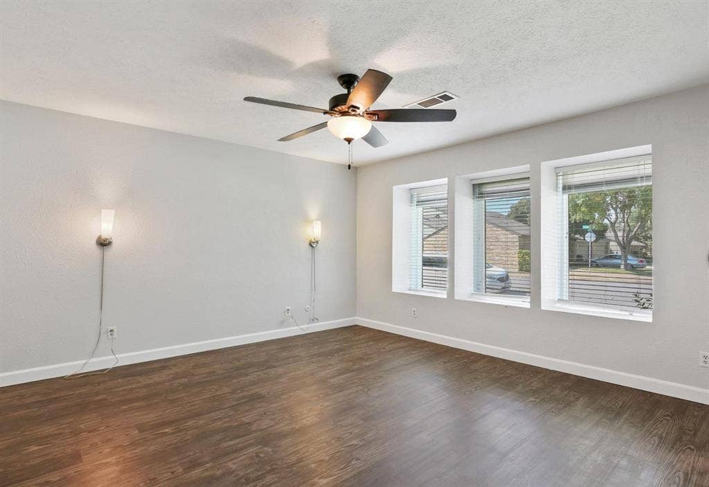 9712 Summerhill Lane, Dallas, TX 75238 Wood-finish flooring, recessed window bays with natural lighting, dual wall-mounted light fixtures, and a central ceiling fan