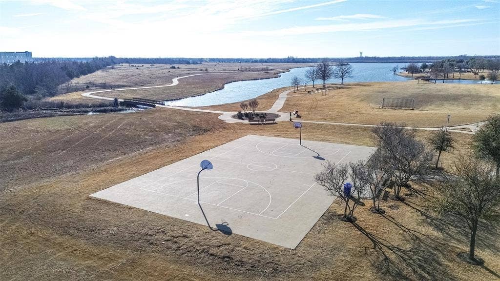 Outdoor concrete basketball court featuring dual goals and paved perimeter walking paths