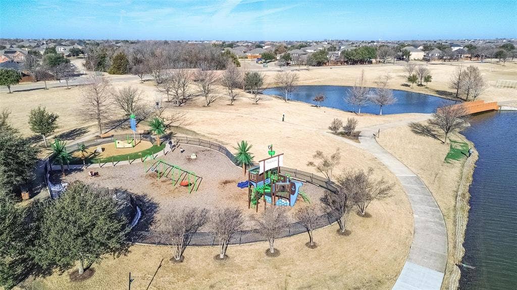 Community park featuring a structured playground, walking paths, expansive open green space, and a waterfront setting