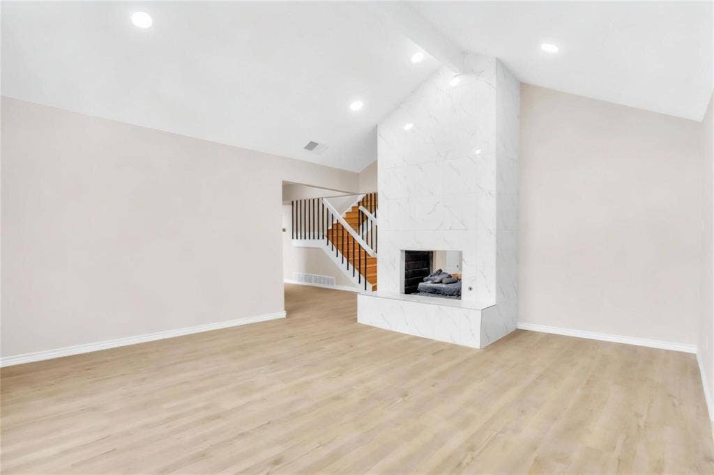 600 Flintridge Court, Irving, TX 75038 Vaulted ceilings, wood-finish flooring, recessed lighting, and a full-height fireplace surround featuring a stone-pattern finish with a matching raised hearth