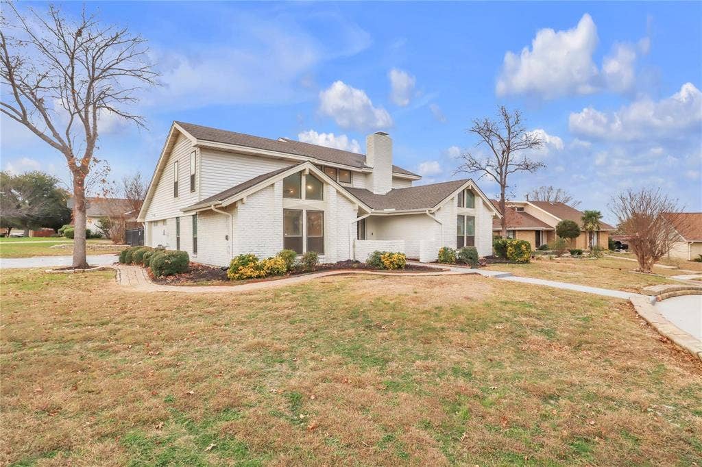 600 Flintridge Court, Irving, TX 75038 Multi-level exterior featuring painted brick and siding, a multi-gabled roofline, floor-to-ceiling windows, and a paved walkway