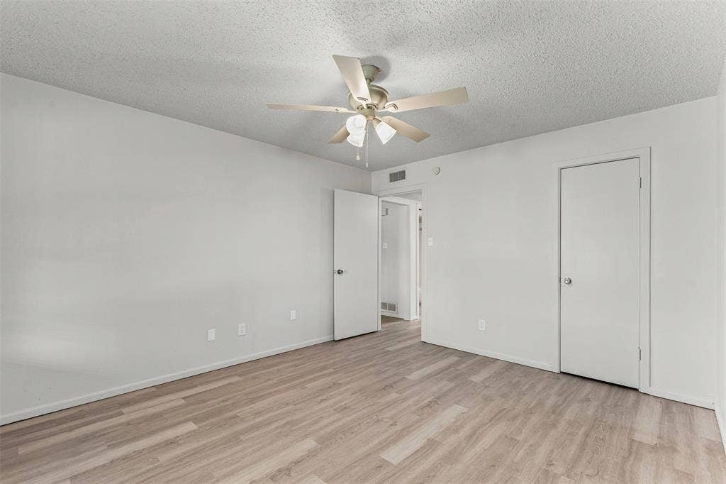 Unfurnished bedroom featuring light wood-style flooring, a textured ceiling, and ceiling fan