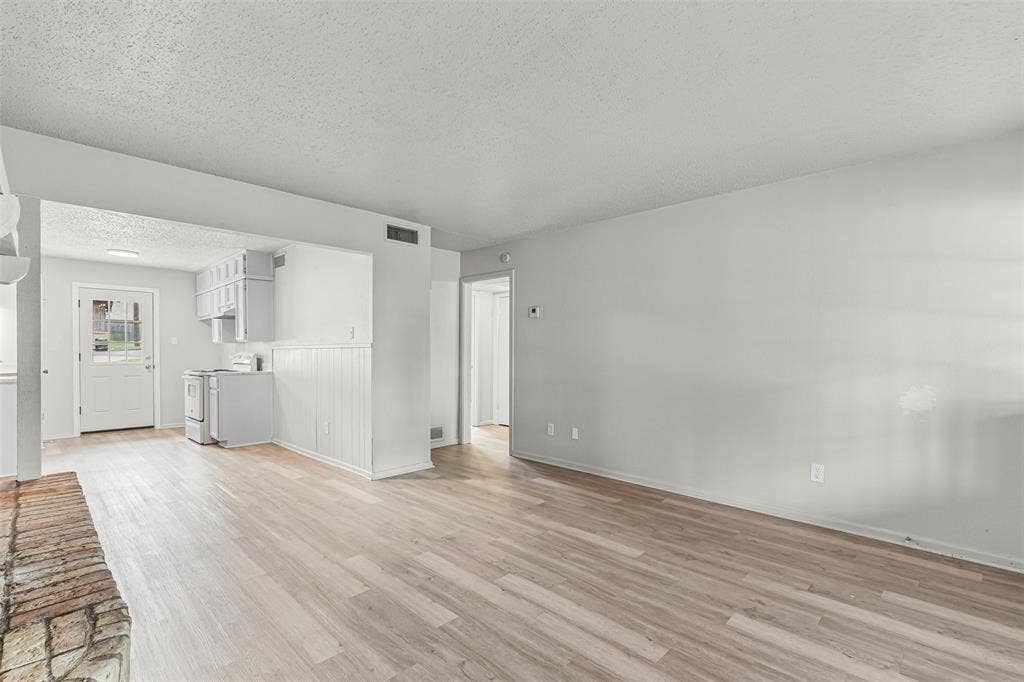 Unfurnished living room with light wood-style flooring and a textured ceiling