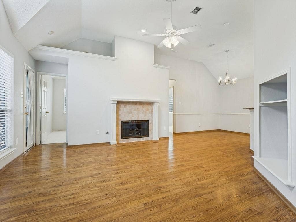 2206 Jasmine Lane, Garland, TX 75044 Vaulted ceilings, laminate flooring, masonry fireplace with a classic mantel, built-in recessed shelving, and a combination of recessed and decorative chandelier lighting