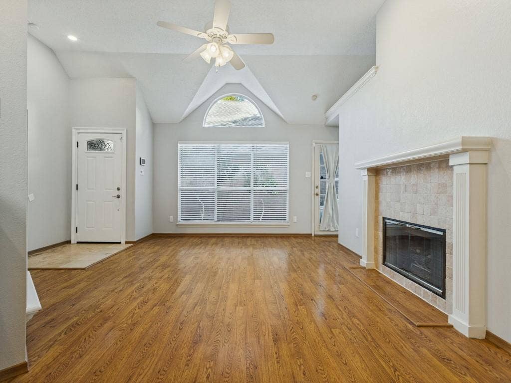 2206 Jasmine Lane, Garland, TX 75044 Vaulted ceilings, laminate flooring, fireplace with a tile surround and mantel, arched window, and central ceiling fan
