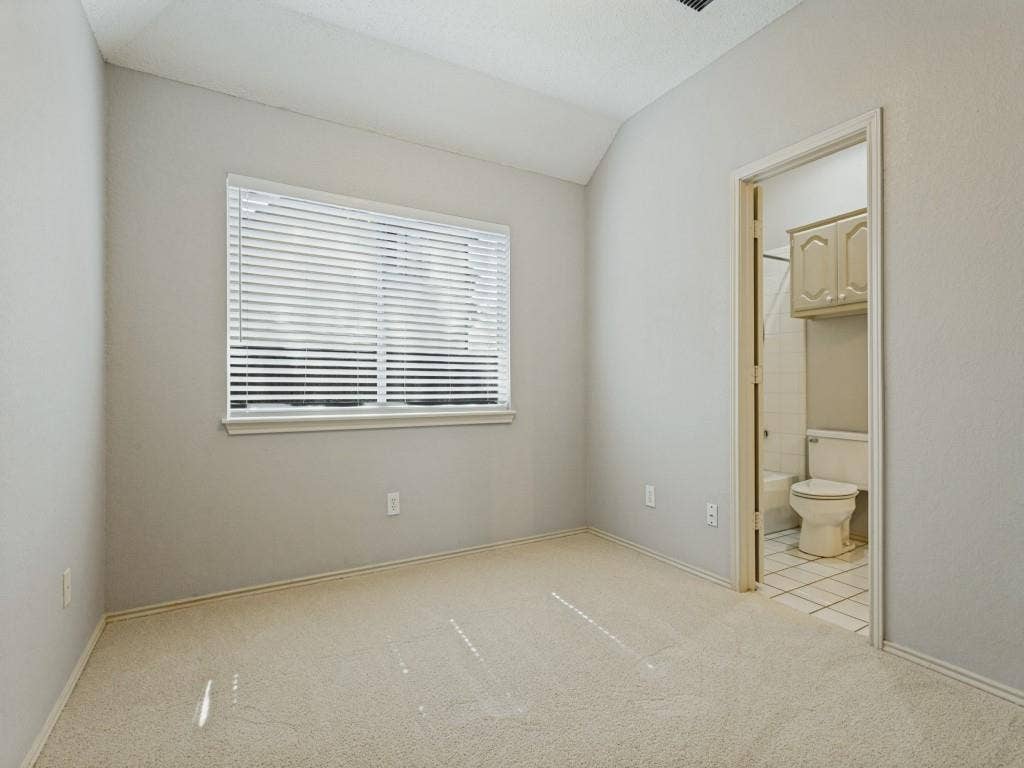 2206 Jasmine Lane, Garland, TX 75044 Neutral carpeting, and horizontal blind, doorway into a tiled bathroom with built-in cabinetry