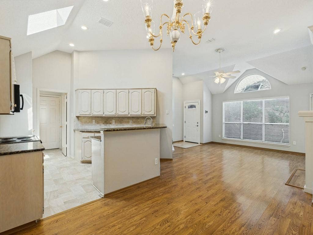 2206 Jasmine Lane, Garland, TX 75044 Vaulted ceilings, laminate flooring, arched window detailing, granite countertops, and ornate chandelier lighting
