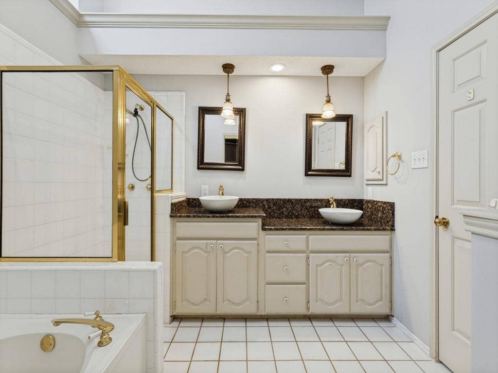 2206 Jasmine Lane, Garland, TX 75044 Dual-vanity cabinetry with dark stone countertops, vessel sinks, pendant lighting, walk-in shower with metal-finish frame, and tile flooring