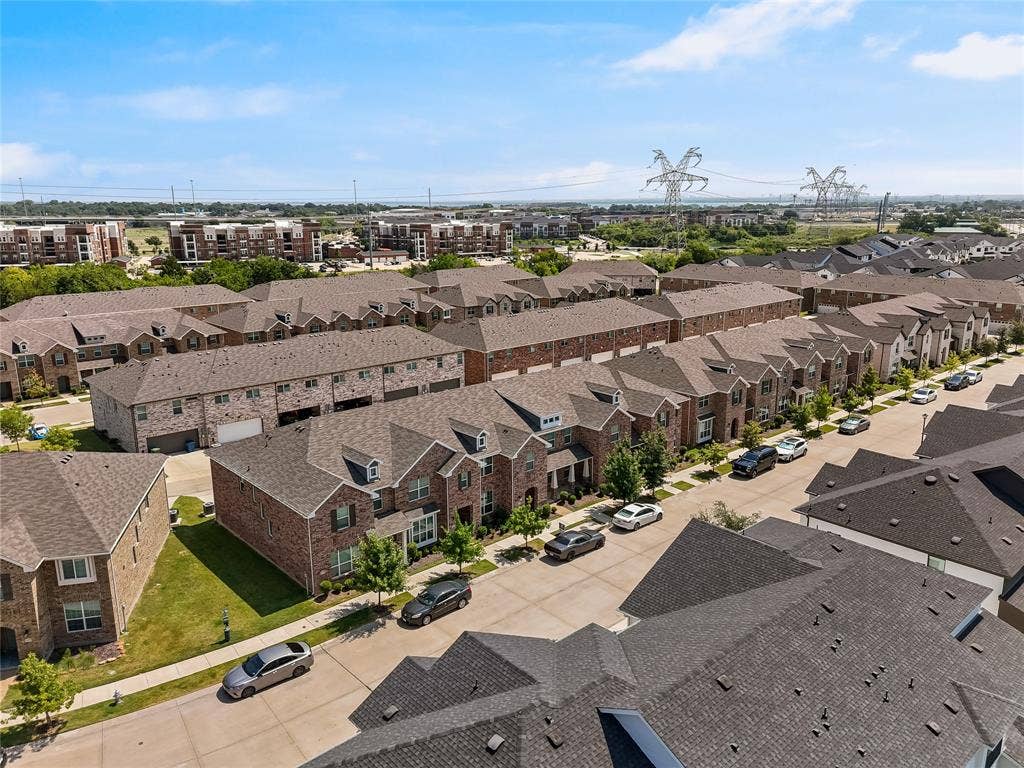 Aerial perspective of a multi-unit residential community featuring brick veneer facades, multi-gabled asphalt shingle roofing, and concrete driveways
