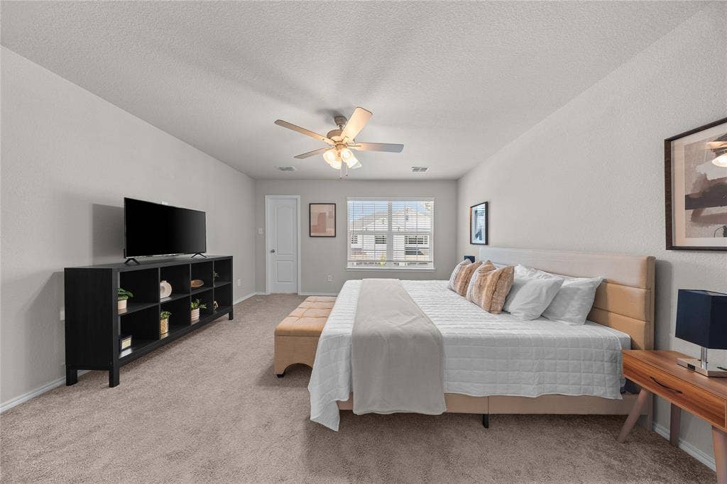 Neutral-toned room featuring wall-to-wall carpeting, a central multi-blade ceiling fan with integrated lighting, and a single-pane window