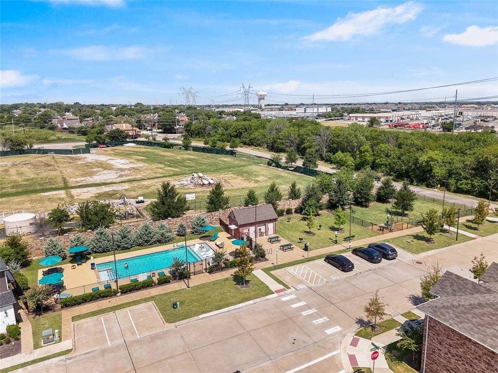 Outdoor swimming pool with concrete decking, clubhouse facility, fenced green space, and designated surface parking