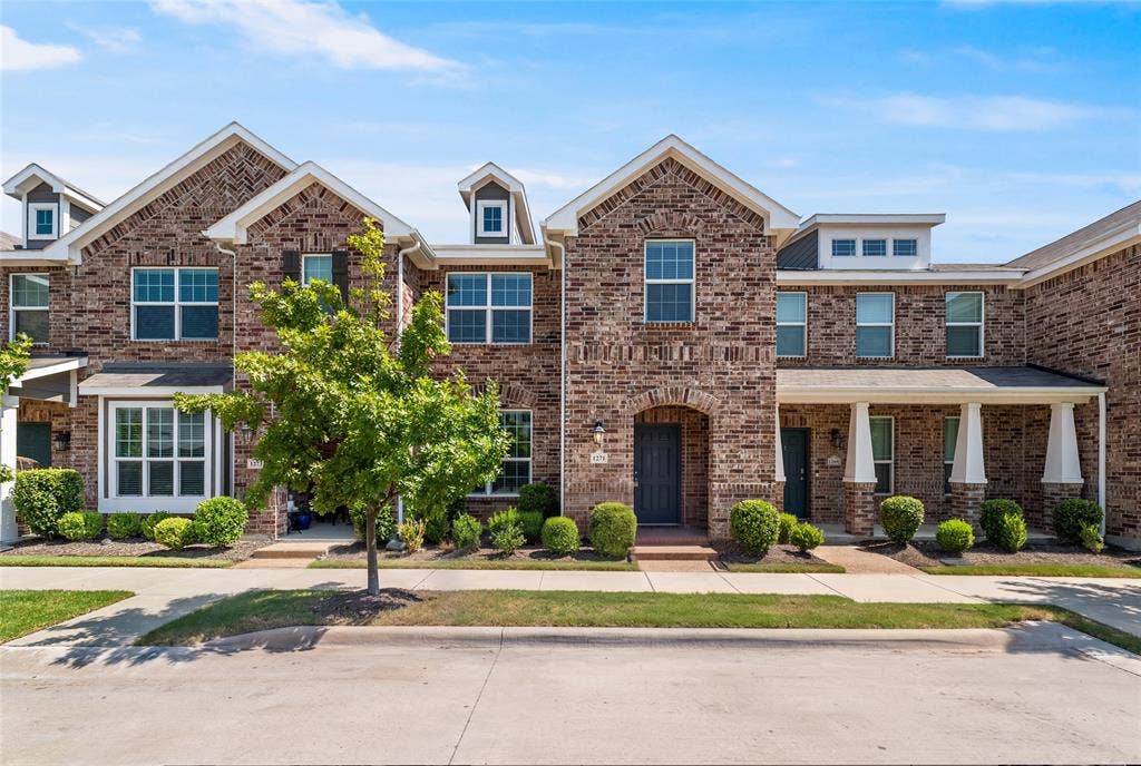 Multi-story brick exterior featuring gable rooflines, multipane windows, and covered porches supported by square columns