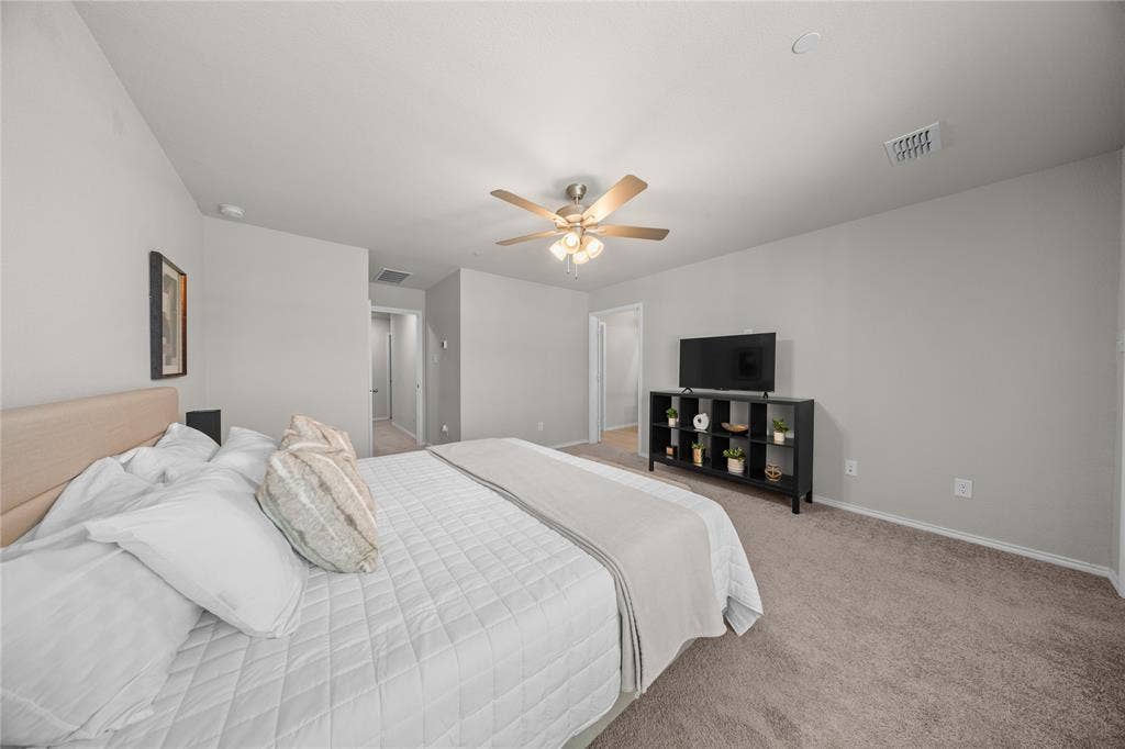 Spacious room featuring neutral wall paint, plush carpeting, and a multi-blade ceiling fan with integrated lighting