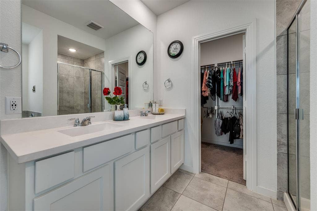 1520 Gelding Drive, Aubrey, TX 76227 Bathroom with double vanity, a shower stall, light tile patterned floors, and a walk in closet