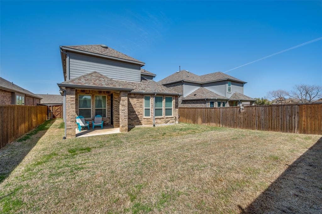 1520 Gelding Drive, Aubrey, TX 76227 Back of property with a fenced backyard, a patio, brick siding, and roof with shingles