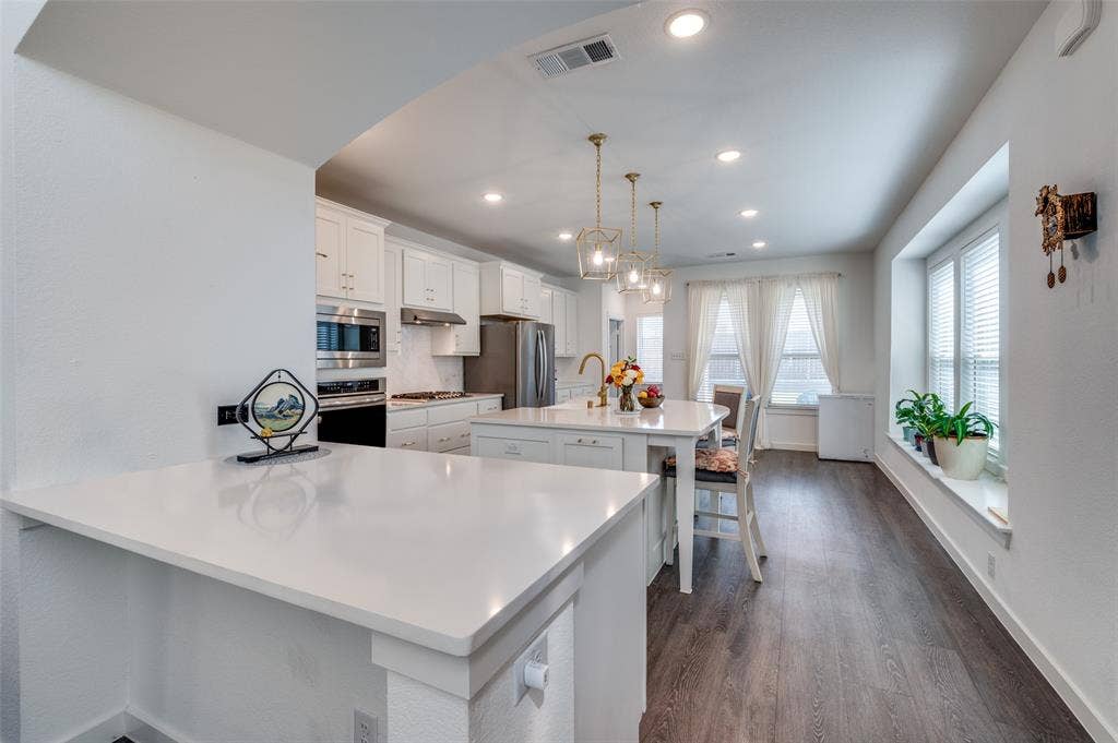1520 Gelding Drive, Aubrey, TX 76227 Kitchen featuring a breakfast bar, hanging light fixtures, white cabinetry, a center island with sink, and dark wood finished floors