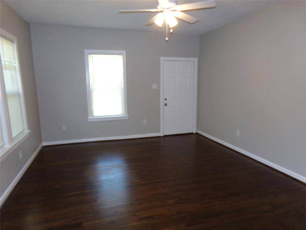 902 Centre Street, Dallas, TX 75208 Interior room featuring wood-finish flooring, neutral wall paint, multi-pane windows, and a ceiling fan with integrated lighting