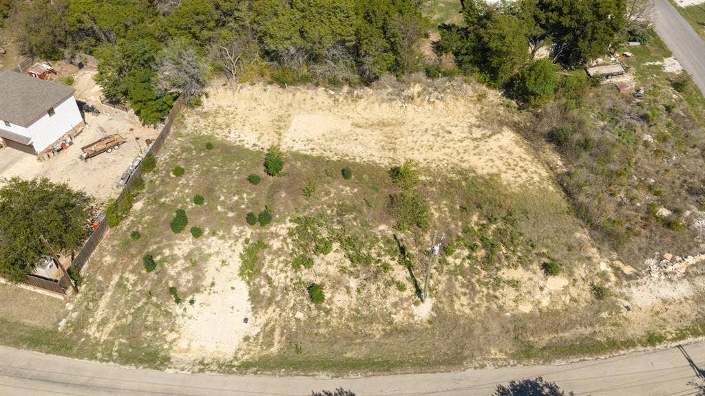 Cleared vacant lot featuring mature trees along the perimeter and paved road frontage
