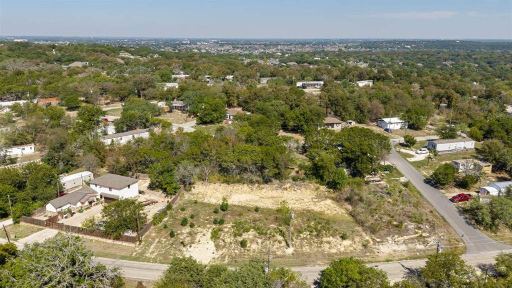 Expansive vacant lot featuring native vegetation, established trees, and prominent street frontage