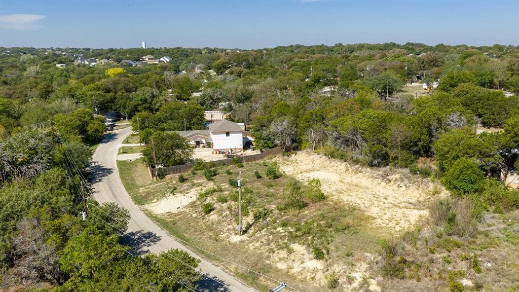 Expansive lot featuring mature trees and significant natural vegetation, situated along a paved road
