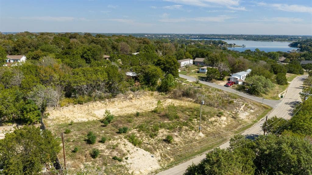 Undeveloped corner lot featuring mature trees, native vegetation, and surrounding water scenery