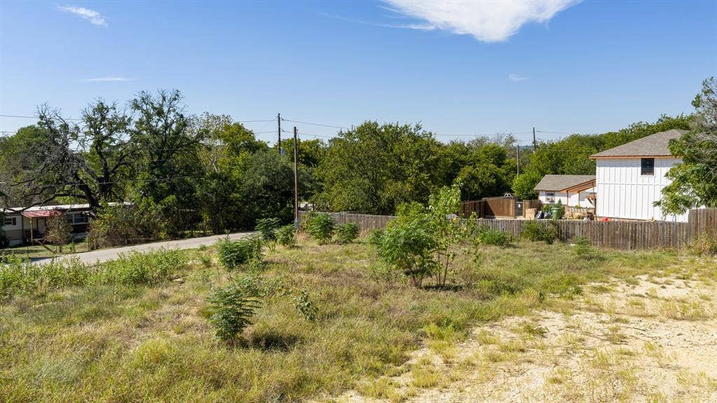 Expansive lot featuring native vegetation, mature trees, and wooden perimeter fencing