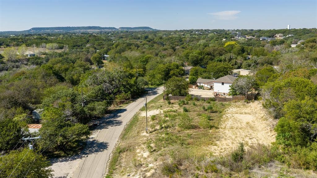 Expansive lot featuring native landscaping, mature tree clusters, and distant mountain topography