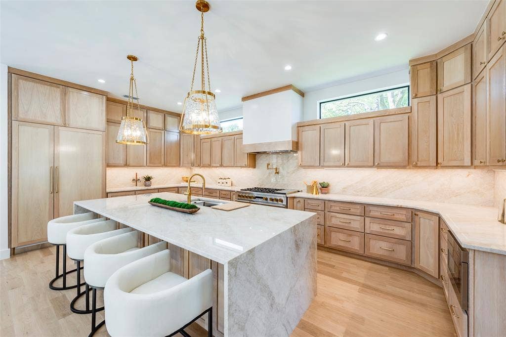 Light filled kitchen with large island, built in Monogram fridge with matching white oak panels