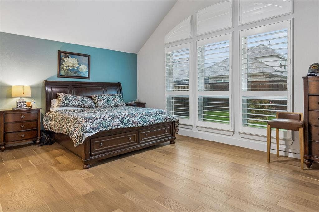 Vaulted ceilings, wood-finish flooring, and expansive windows featuring plantation shutters
