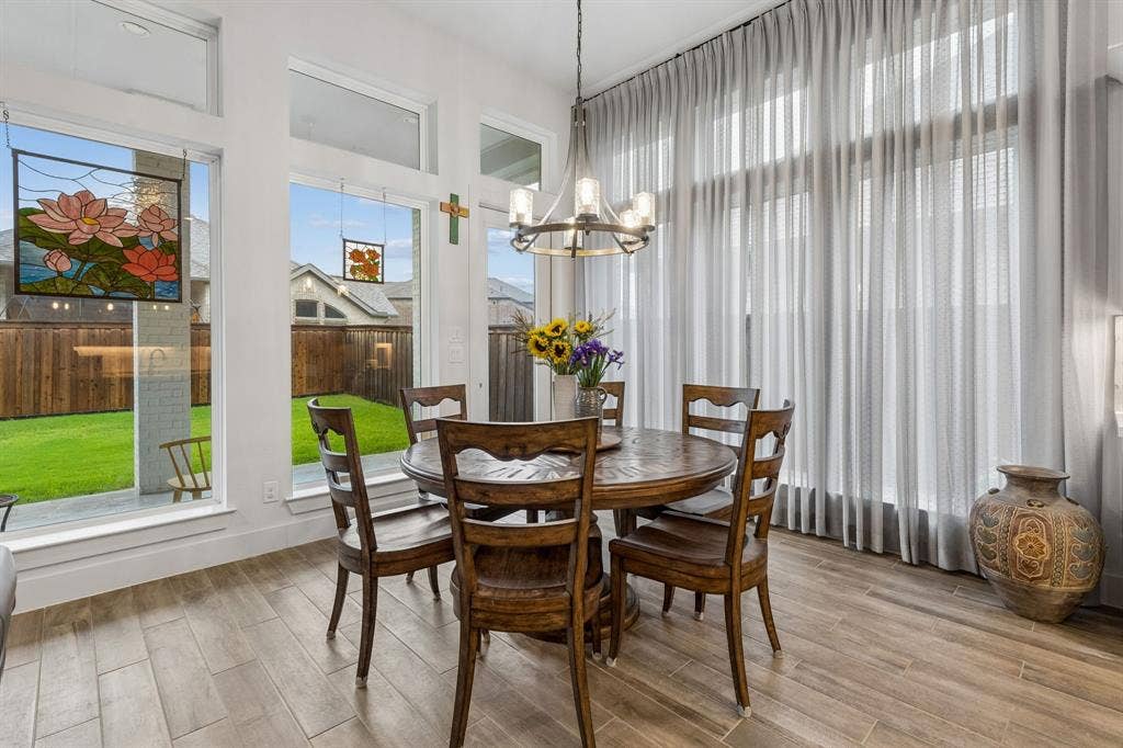 Dining area featuring floor-to-ceiling windows, wood-finish tile flooring, an iron chandelier, and neutral wall tones