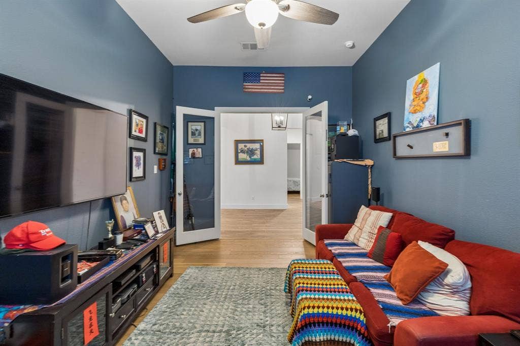 High ceilings featuring a central light fixture with a ceiling fan, complemented by wood-finish flooring and double glass-panel doors