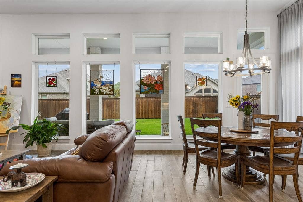 Expansive floor-to-ceiling windows with upper transoms, wood-finish tile flooring, and a tiered metal chandelier
