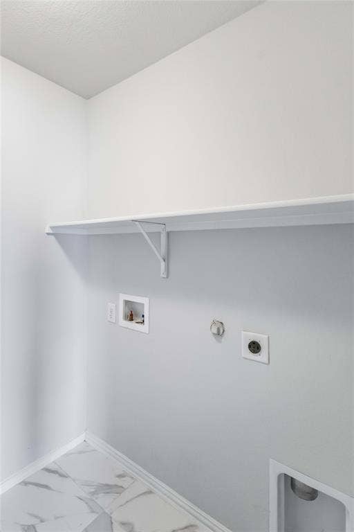 Utility area featuring white-finish walls, stone-look tile flooring, a wall-mounted shelf, and dedicated water and electrical hookups