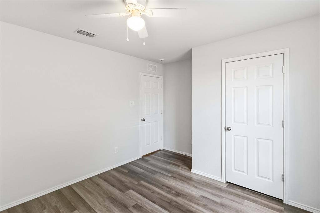 Interior room featuring wood-finish flooring, neutral wall paint, and a ceiling-mounted light fixture with an integrated fan