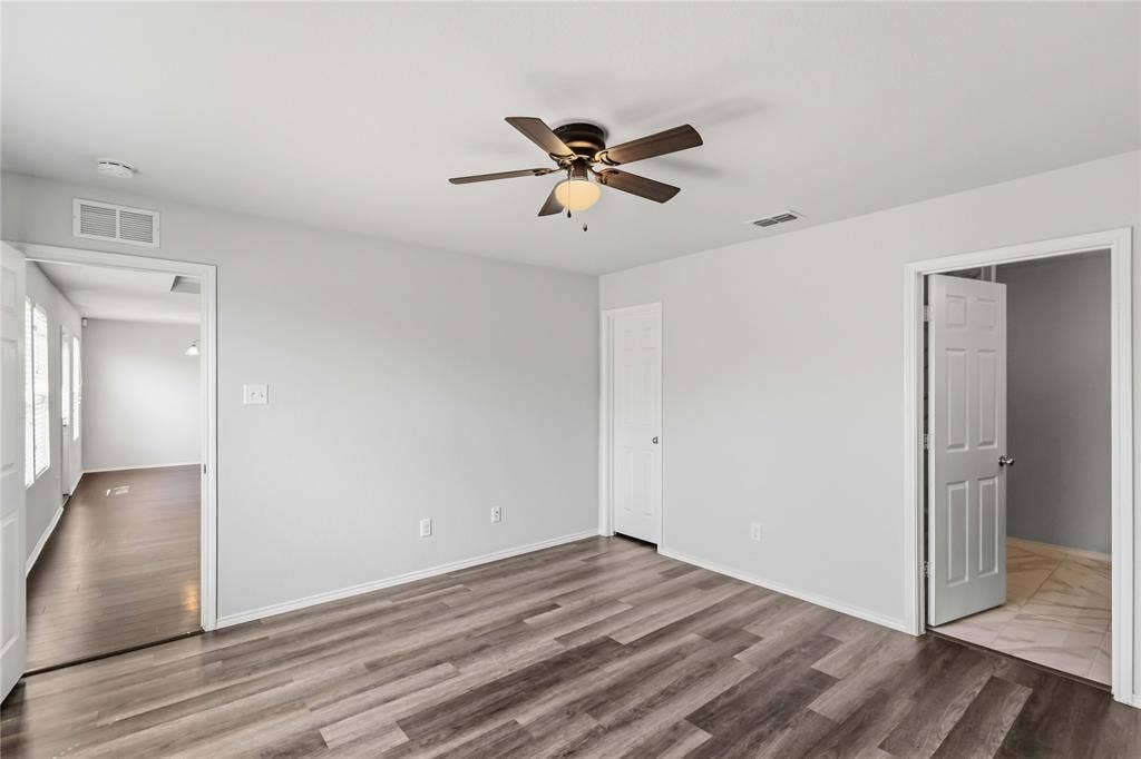 Neutral-toned interior featuring wood-finish flooring, a ceiling fan with integrated lighting, and six-panel interior doors