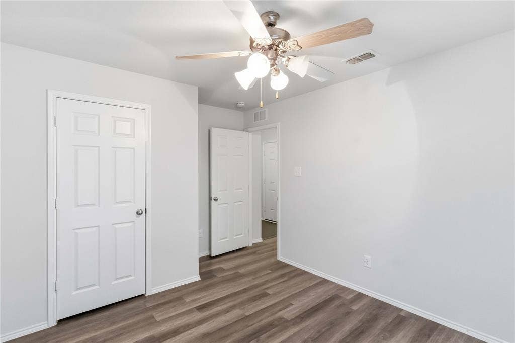 Interior space featuring wood-finish flooring, a multi-light ceiling fan with neutral-finish blades, and white six-panel interior doors