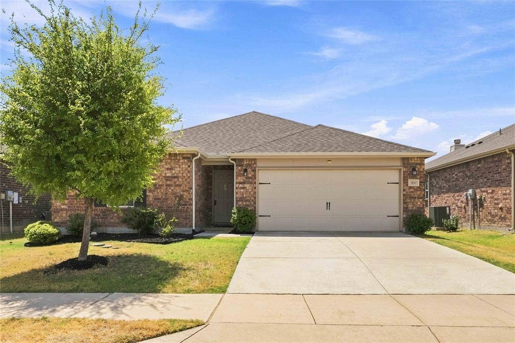 Single-story residence featuring a brick exterior, shingled roof, attached two-car garage, and a concrete driveway