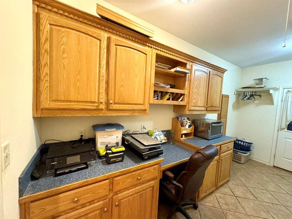 3700 NE County Road 0095, Corsicana, TX 75109 Custom cabinetry with crown molding, integrated open shelving, solid-surface countertops, and ceramic tile flooring