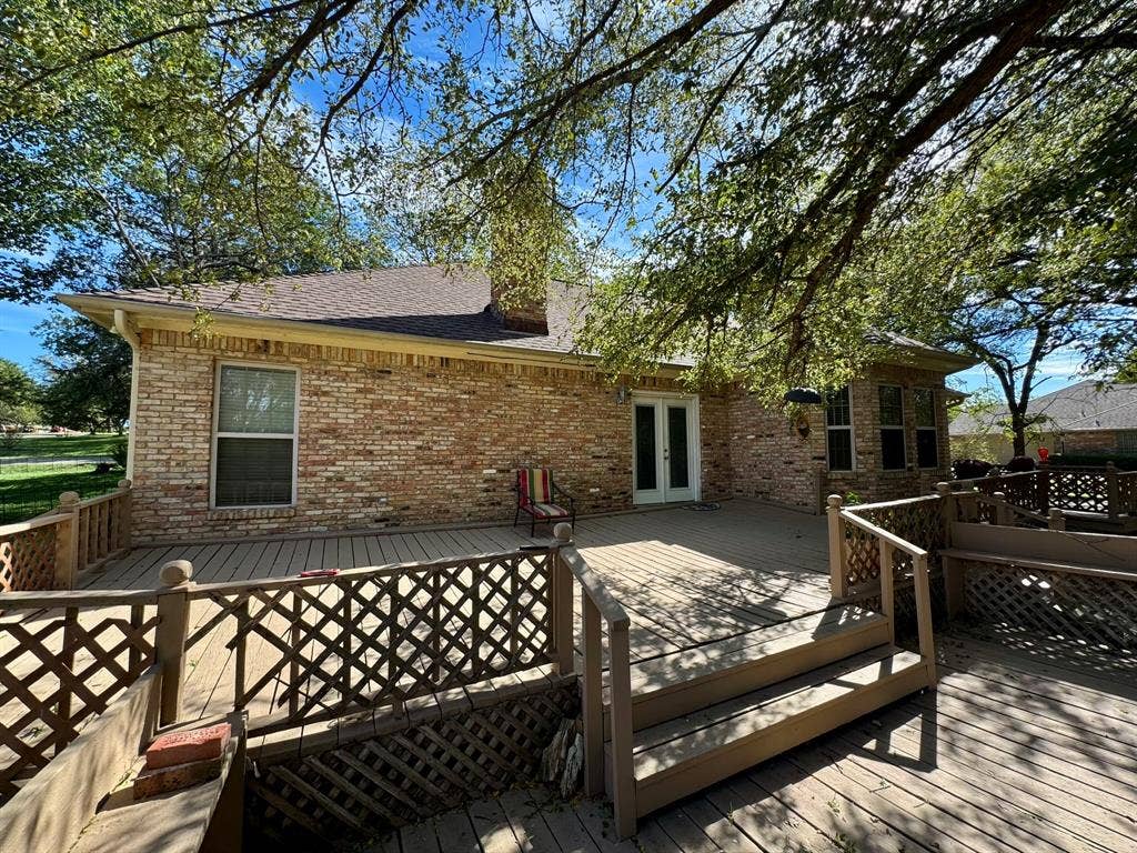 3700 NE County Road 0095, Corsicana, TX 75109 Multi-level wood deck featuring lattice railing, brick exterior, chimney, and glass-paneled double doors