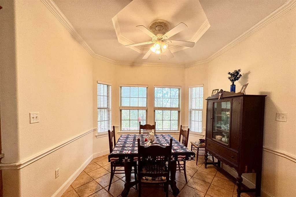 3700 NE County Road 0095, Corsicana, TX 75109 Octagonal tray ceiling, tile flooring, crown molding, chair rail trim, and a multi-light ceiling fan