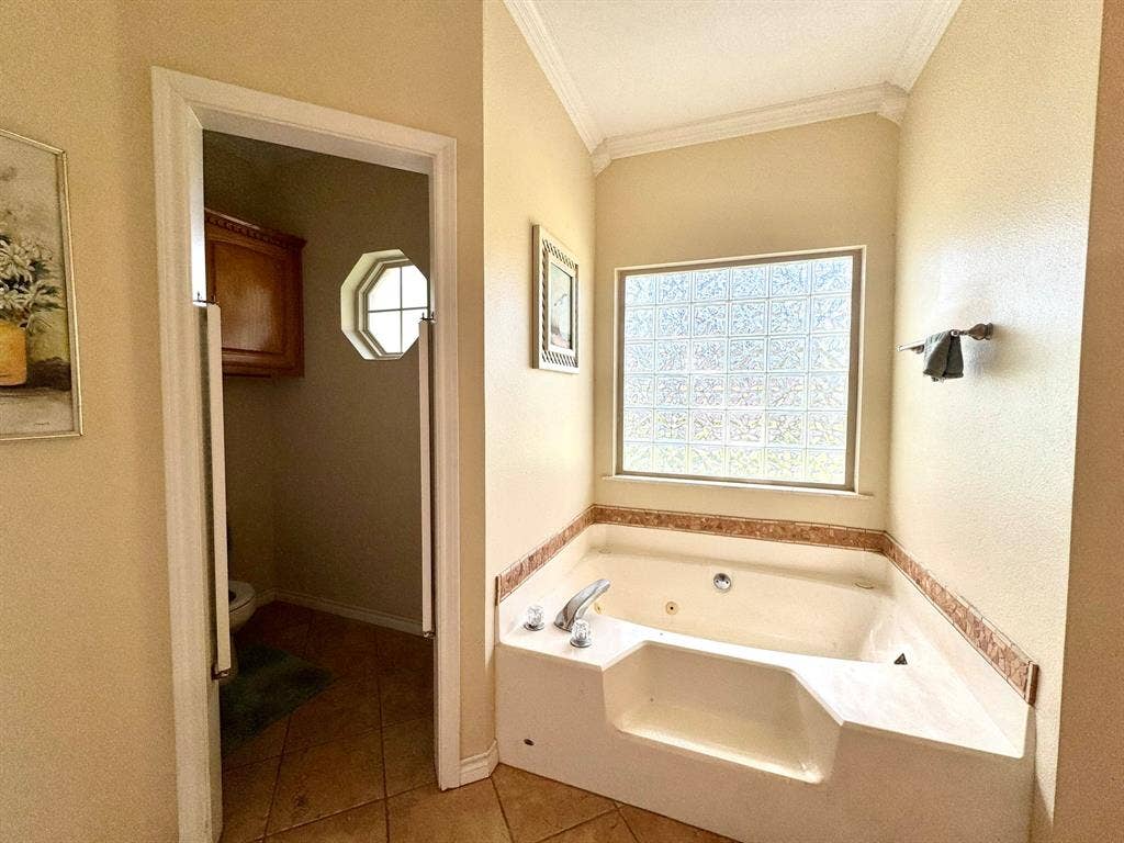 3700 NE County Road 0095, Corsicana, TX 75109 Corner jetted tub with tile surround, glass block window, crown molding, and tiled flooring
