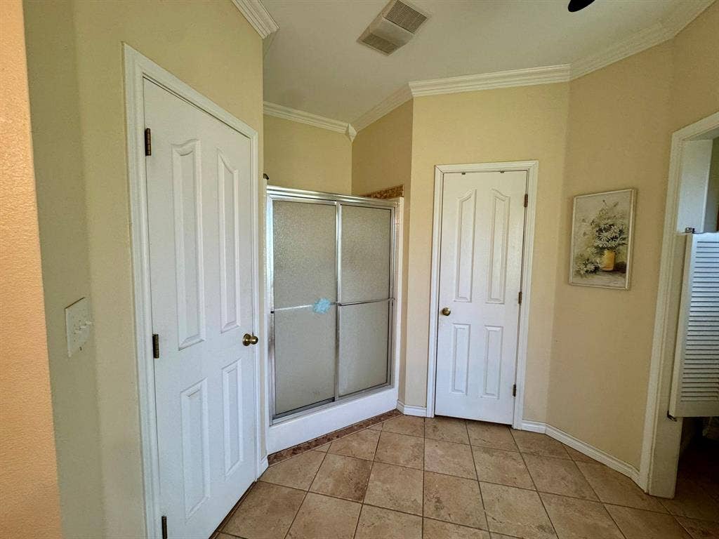 3700 NE County Road 0095, Corsicana, TX 75109 Ceramic tile flooring, crown molding, and a walk-in shower with a metal frame enclosure