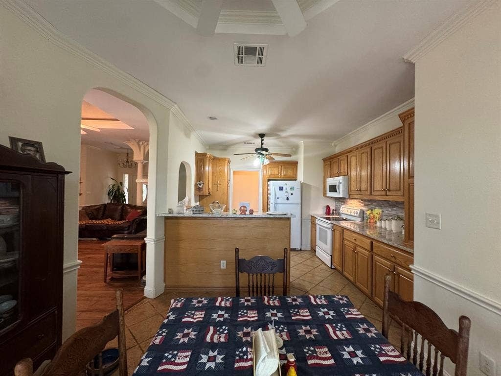 3700 NE County Road 0095, Corsicana, TX 75109 Kitchen featuring wood cabinetry, stone-finish countertops, tile flooring, and a breakfast bar with built-in millwork